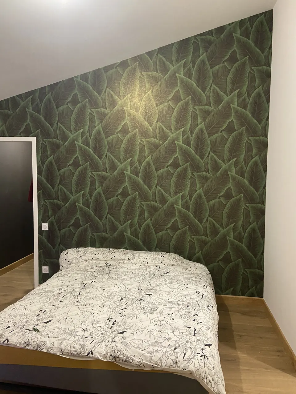 Pose d'une tapisserie, au motif végétal, sur un pan de mur d'une chambre